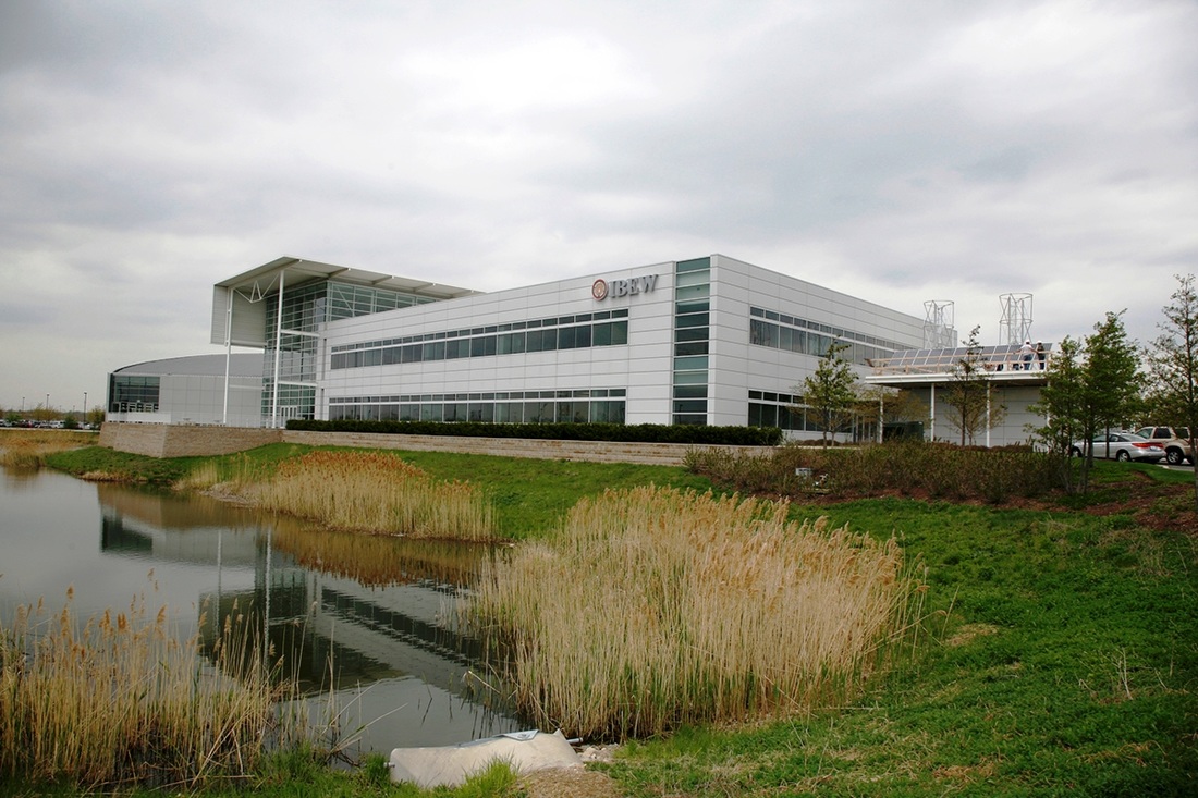 Photo showing IBEW Local 701 Building with two employees installing solar panels on the side.